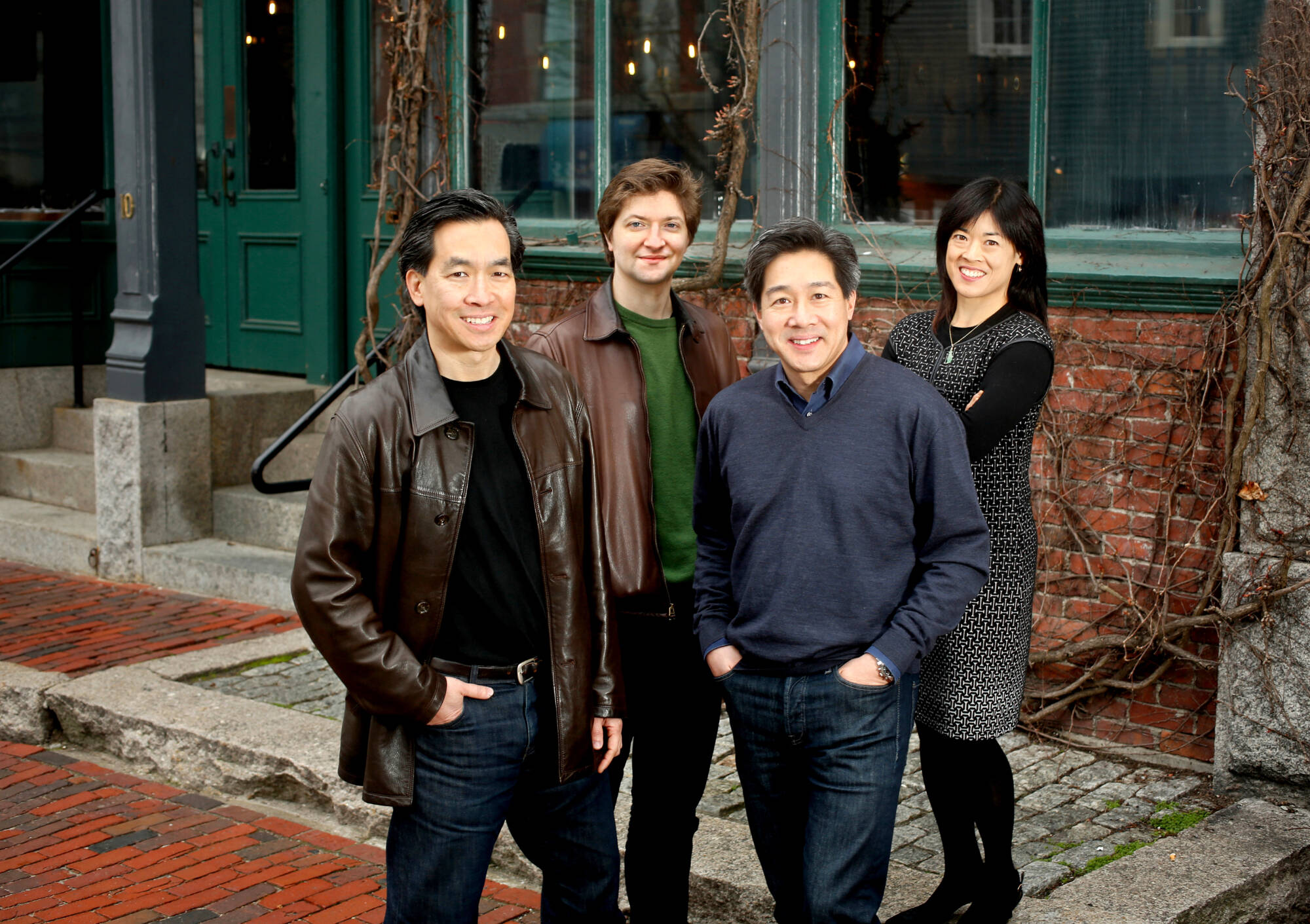 four people stand on the street with their hands in their pockets